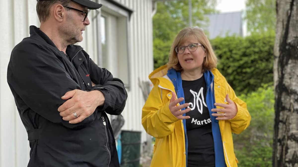 Mies juttelee naisen kanssa pihalla. 