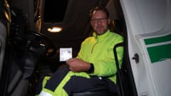 Mika Vaittinen istuu rekan nupissa ja pitää kädessään heijastinta.