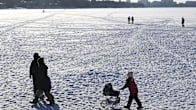 Ihmisiä kävelemässä meren jäällä aurinkoisessa pakkassäässä.