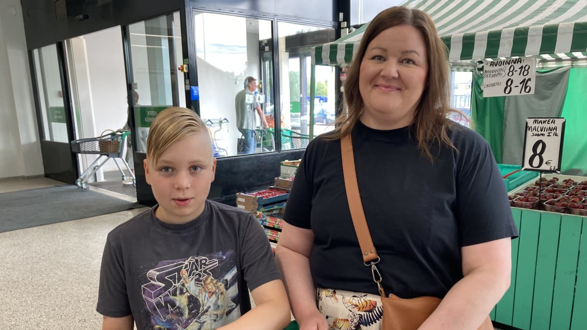 Poika ja hänen äitinsä seisovat marketin sisääntuloaulassa.