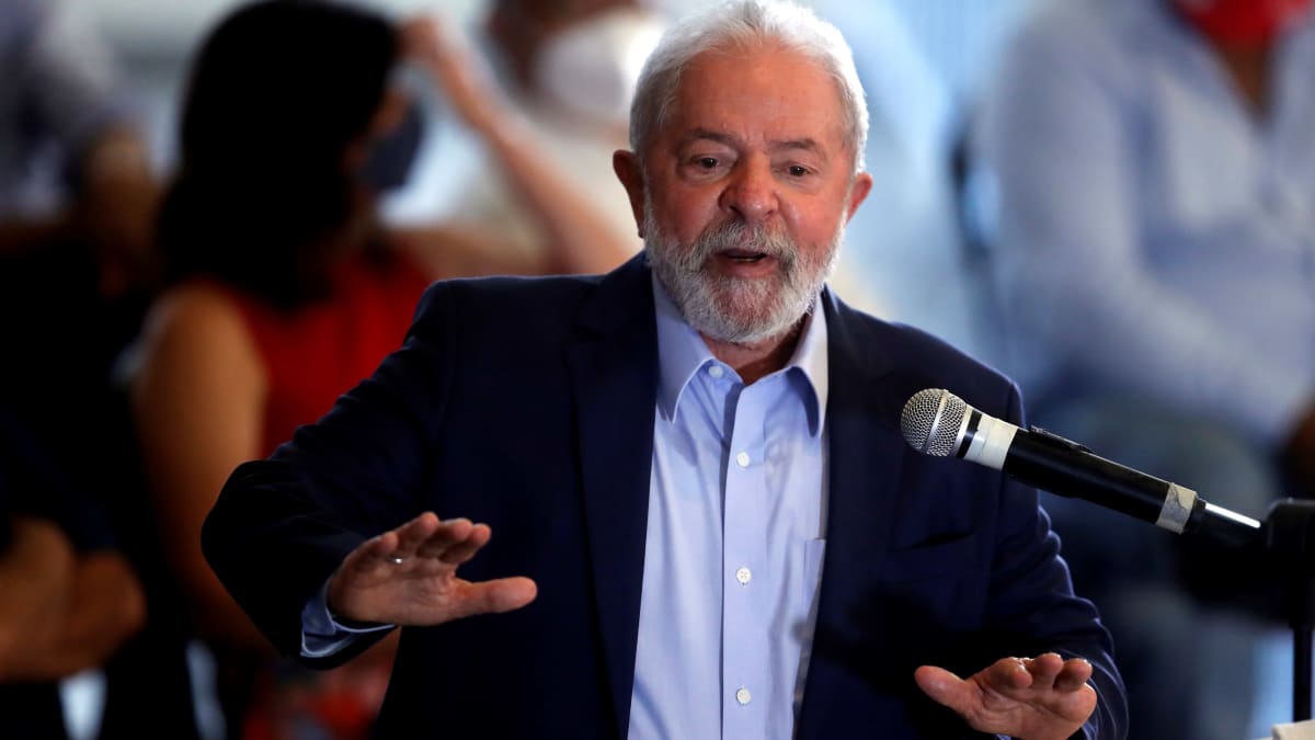 Lula da Silva on nostanut kätensä ylös eteensä kämmenet alaspäin. Hän on korokkeella ja puhuu mikkiin.