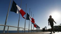 Merenrannalla on rivissä kolme Ranskan lippua, jotka liehuvat puolitangossa.