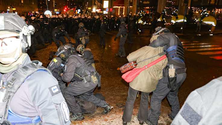 Mellakkapoliisit ottavat mielenosoittajia kiinni.
