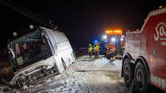 Lumisella tiellä kyljelleen kaatunut linja-auto ja pelastuslaitoksen työntekijöitä.