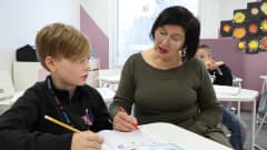 Karsikon koulun 3A-luokan opettaja Merja Jukarainen näyttää oppilas Lenni Korpisalolle, miten matematiikantehtävä ratkaistaan.