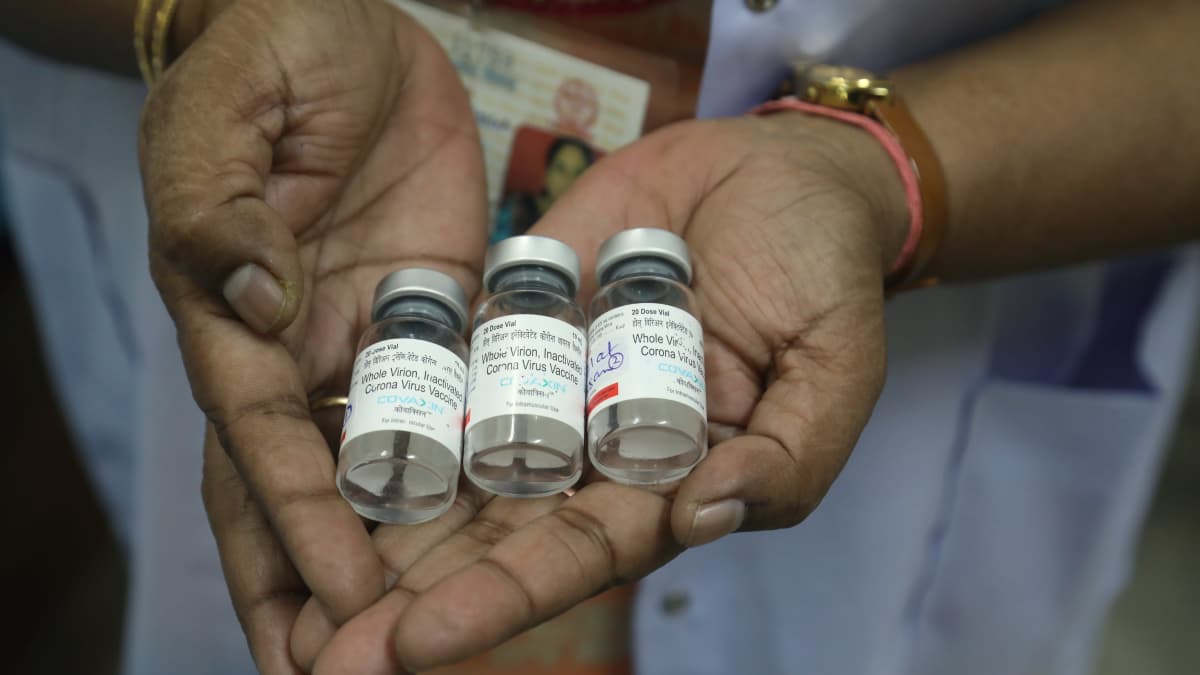 Terveydenhuollon työntekijä pitelee tyhjiä rokotepulloja Intiassa