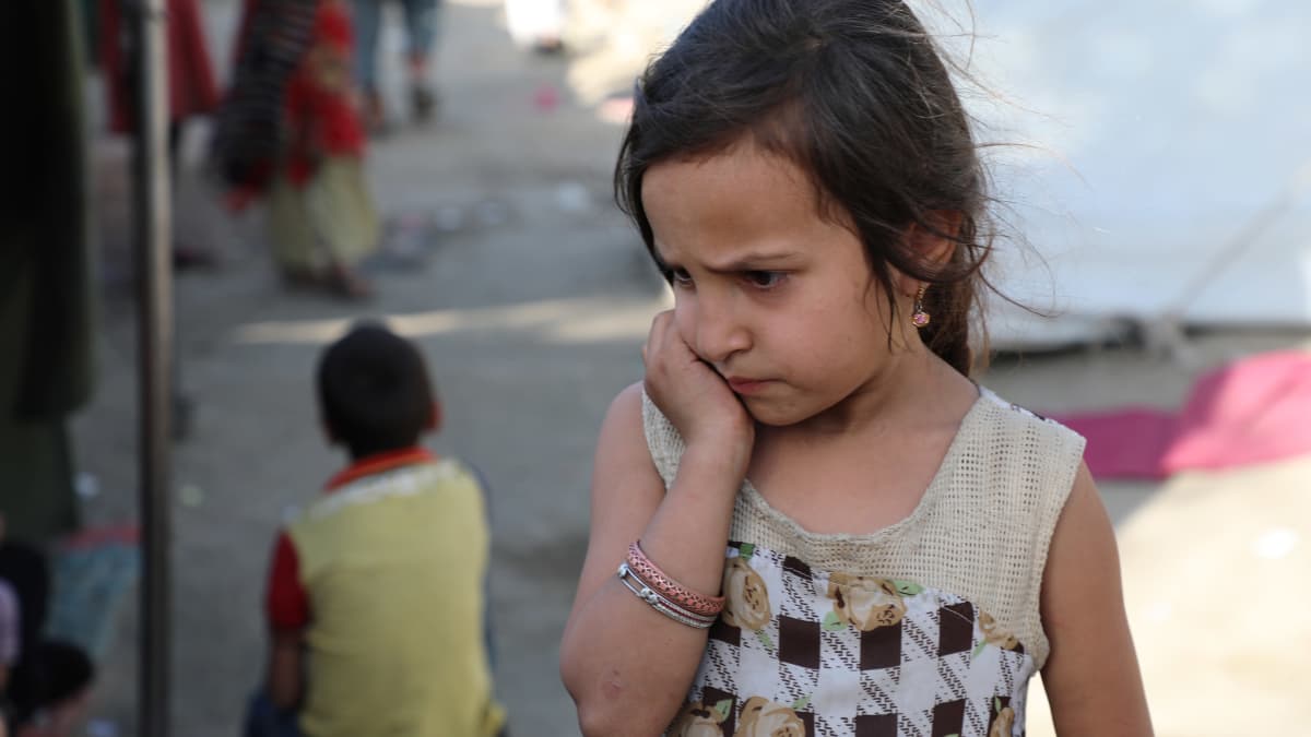 Tyttö nojaa kädellään poskeen kabulilaisella pakolaisleirillä