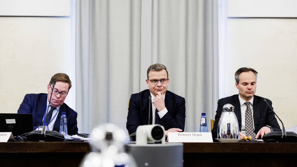 Secretary of the NCP parliamentary group Mikko Kortelainen, NCP leader Petteri Orpo, and chair of the NCP parliamentary group Kai Mykkänen sit at a table.