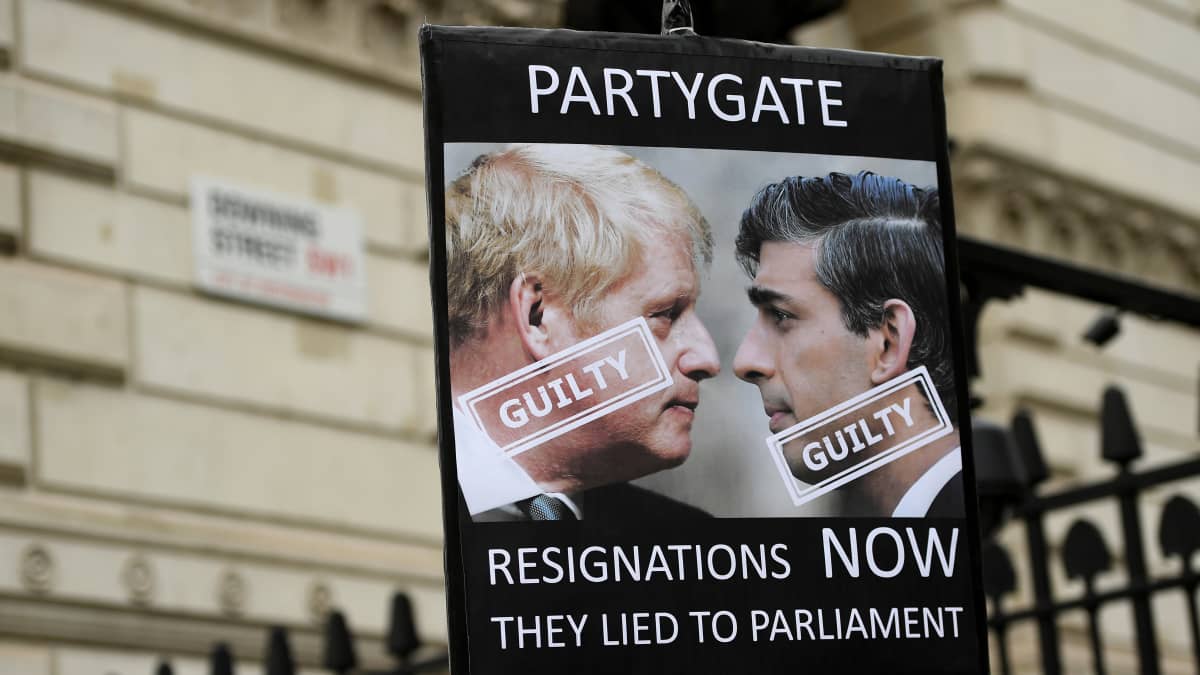 Boris Johnson ja Rishi Sunak kyltissä jossa lukee guilty eli syyllinen ja partygate