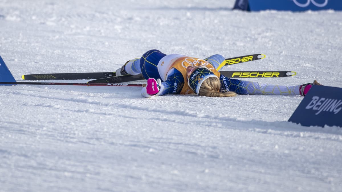 Frida Karlsson makaa uupuneena maassa Pekingin olympialaisten viestiosuutensa jälkeen.