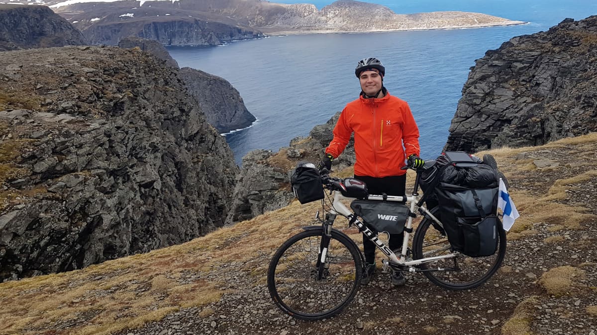 Teemu Hartman seisoo pyöränsä vieressä Norjassa kallioisella rannalla.