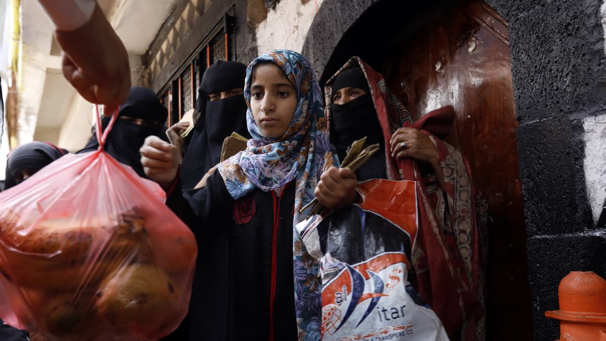Jemeniläinen tyttö vastaanottaa ruokaa Jemenissä.