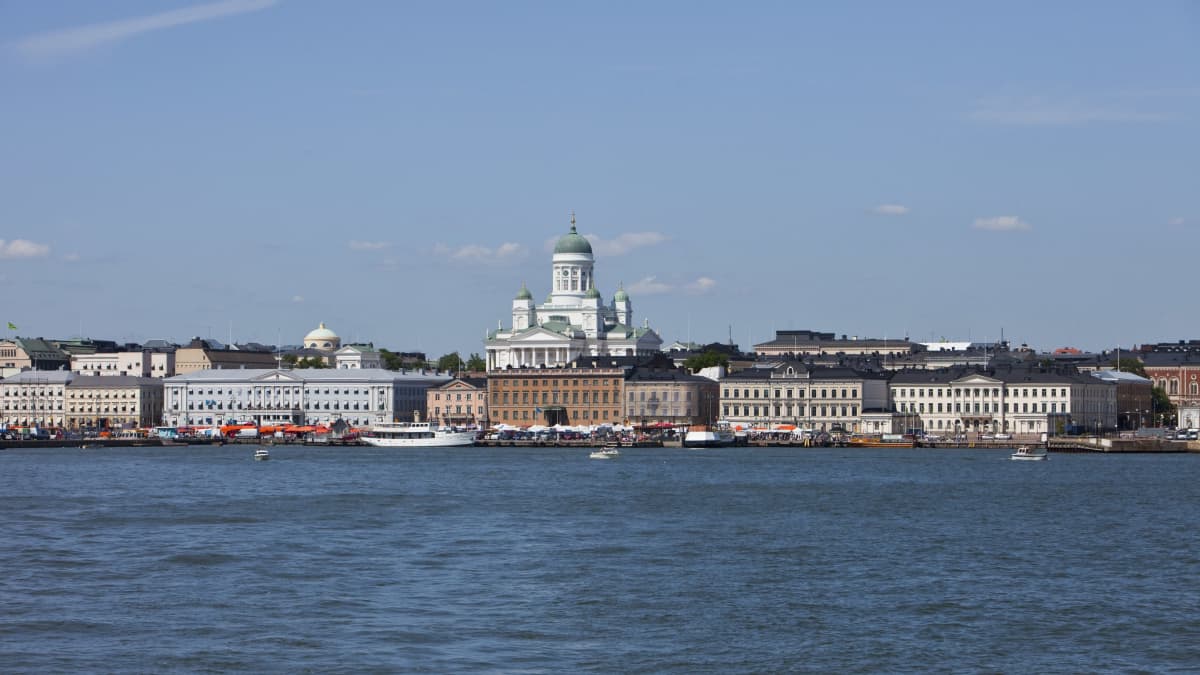 Helsingin kauppatori mereltä nähtynä. Kesäpäivä. Kirkko ja oranssit myyntikojut. Kaupungin siluetti.