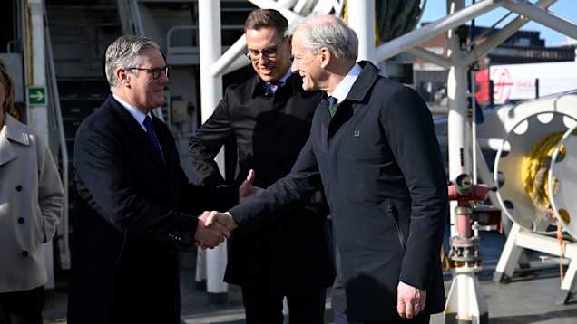 Miehet kättelevät laivan kannella.