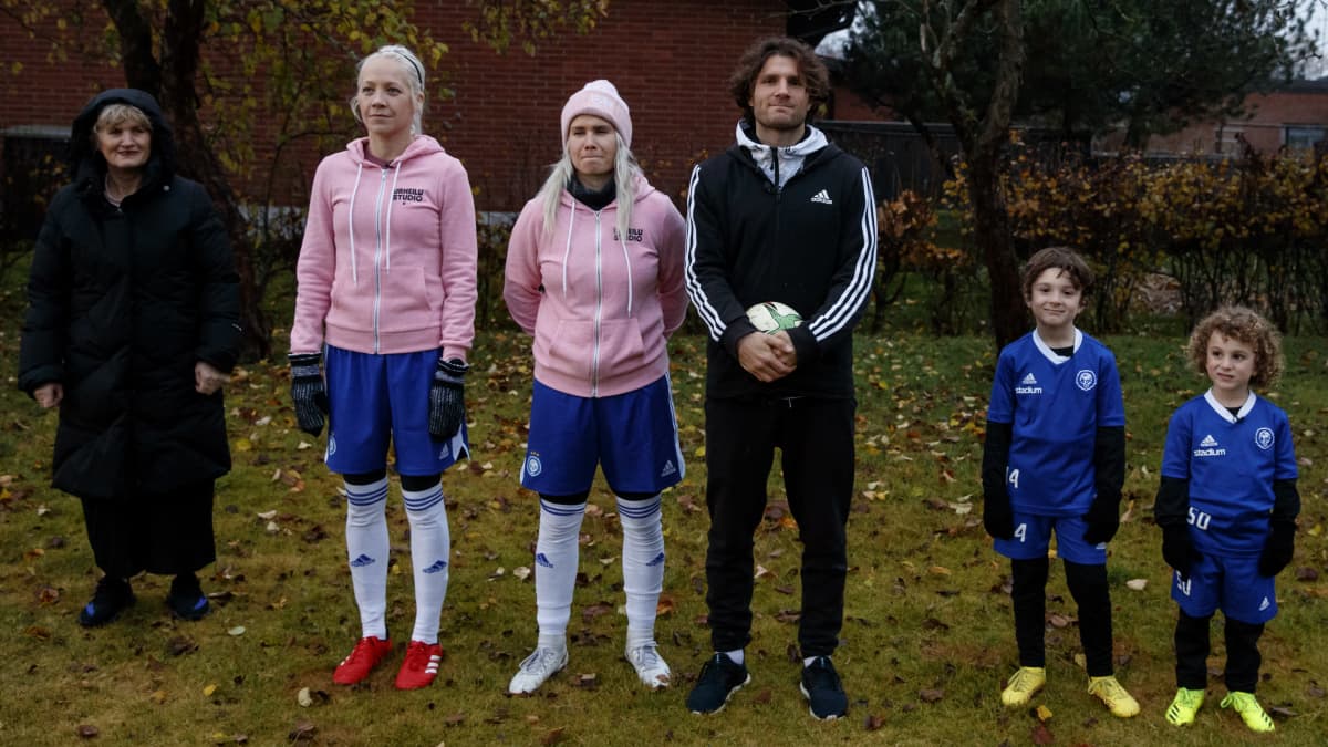 Kaisa Mäkäräinen, Petra Olli ja Perparim Hetemaj seisovat vierekkäin Hetemaj'n perheen kanssa pihalla.
