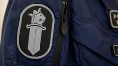 Poliisin virkamerkki työhaalarin hihassa