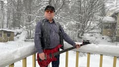 Mies seisoo lumisateessa basson kanssa