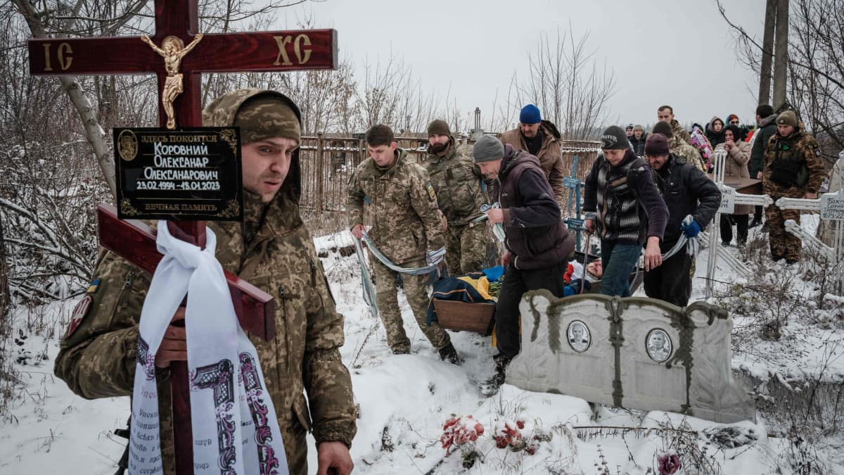 Mies kantaa ristiä hautajaisissa hautausmaalla Slovjanskissa, Ukrainassa.