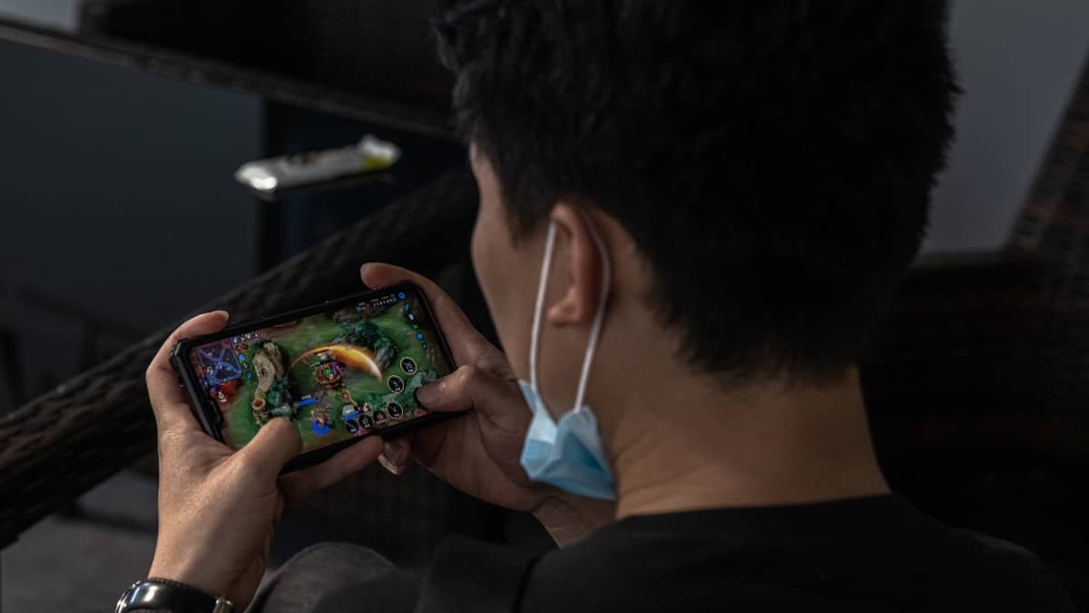 Mies pelaa huippusuosittua Honor of Kings -nettipeliä puhelimellaan Sanlitunissa Pekingissä. Verkkojätti Tencentin peliä pelaa keskimäärin 100 miljoonaa käyttäjää päivittäin ja se on yksi Kiinan suosituimmista..