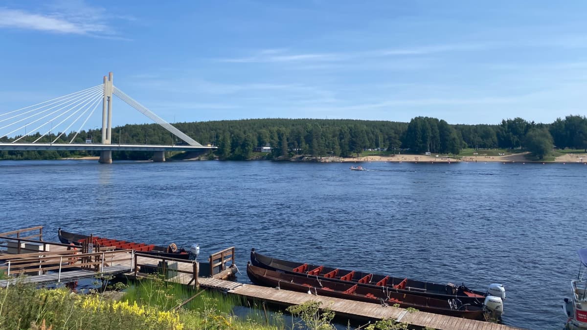 Jätkänkynttiläsilta taustalla, edustalla jokiveneitä ja Kemijoki. 