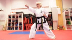 Salme Nummela taekwondo-asennossa, katsoo kameran ohi hymyillen. 