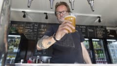 Hämeenlinnan Toribaarin työntekijä Arto Luhtavaara seisoo baaritiskin takana ja kohottaa oluttuoppia.