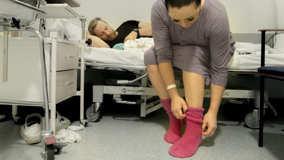 Sinikka Ijäs laittaa jalkaan valitsemaansa Marttojen ensisynnyttäjille neulomaa sukkaparia.