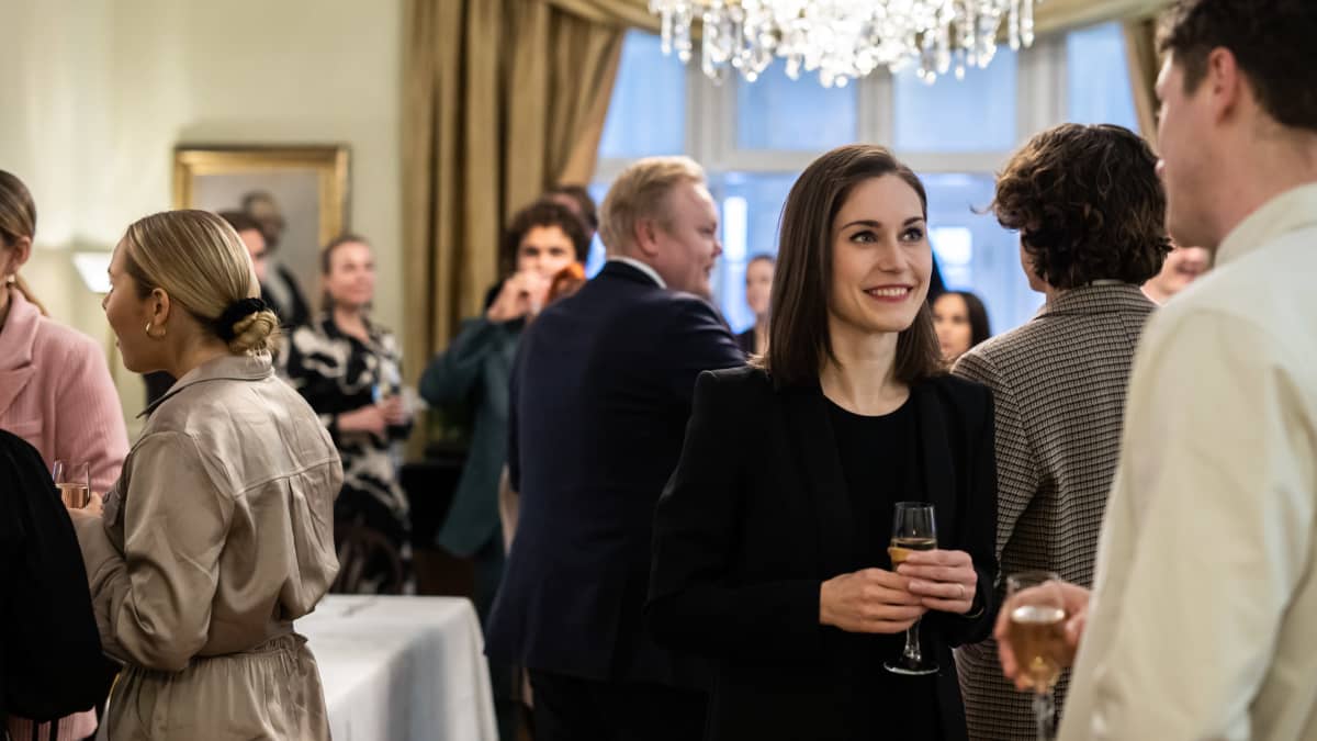 Sanna Marin keskustelee mieshenkilön kanssa juhlavissa tunnelmissa.