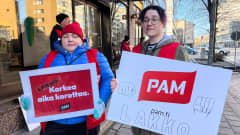 Kaksi naista pitelee PAMin lakkokylttejä käsissään Turun keskustassa. 