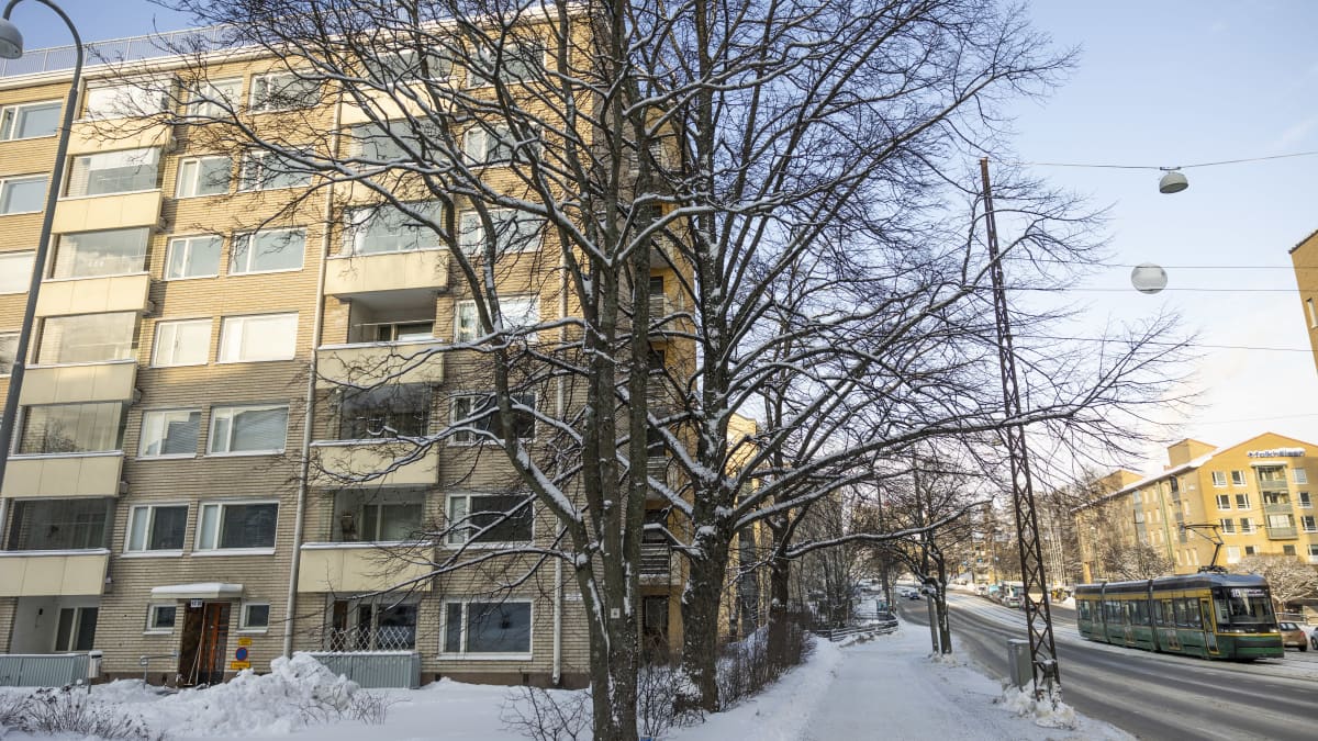 Kerrostalo, jonka vieressä kulkee Mannerheimintien kevyenliikenteen väylä, autotie ja raitiotie. Tiellä raitiovaunu.