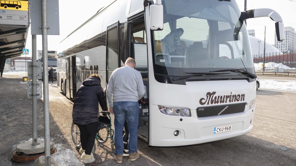 Bussikuljettaja auttaa liikuntavammaista Ukrainan pakolaista bussiin.
