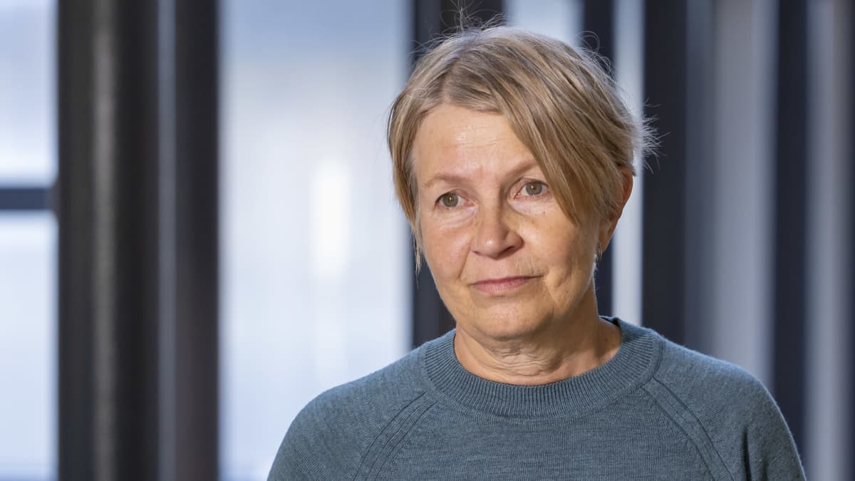 Tuija Leino turkoosissa neuleessa THL:län aulassa.