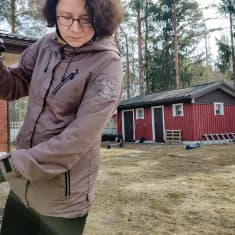 Nainen haravoi keväistä omakotitalon pihaa