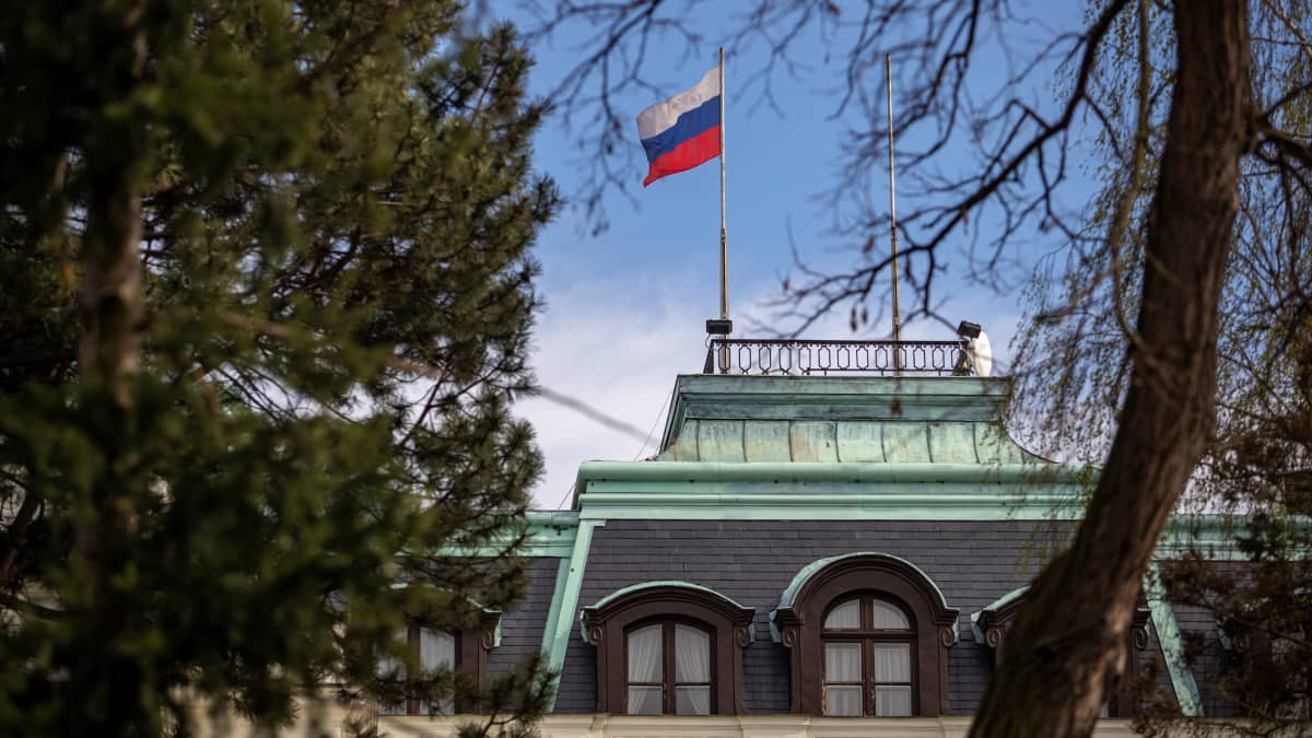 Venäjän lippu liehuu lähetystörakennuksen katolla. Kuvaa reunustavat puut.