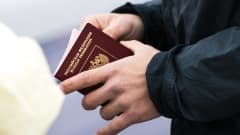 En person håller i ett ryskt pass. Närbild.