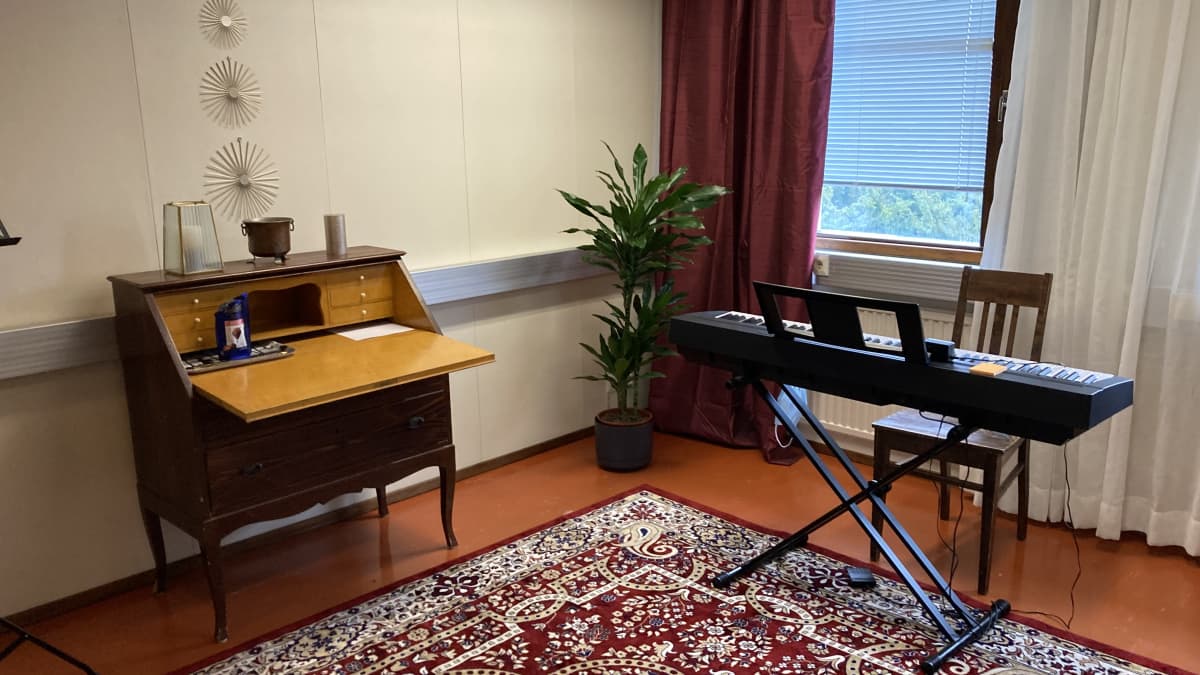 huone jossa on sähköpiano ja lipasto punaisella matolla