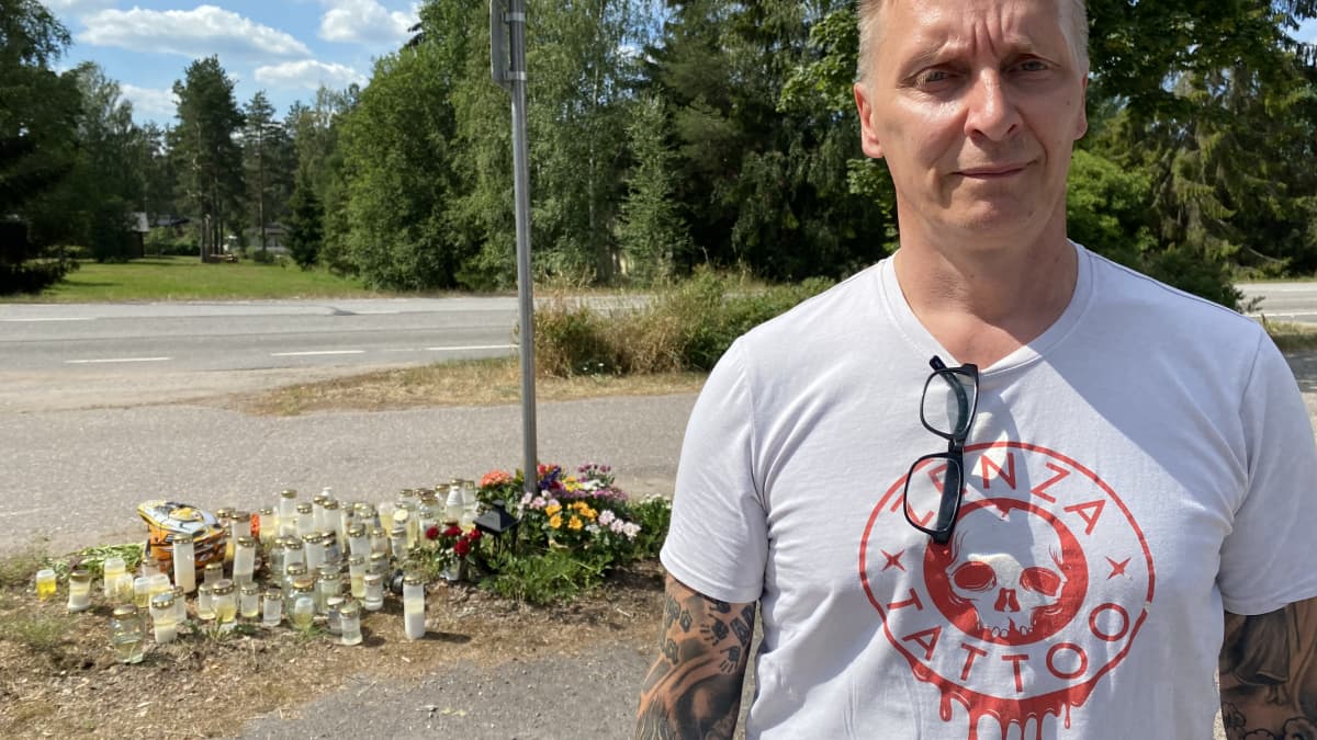 T-paitaan pukeutunut mies seisoo tienvarteen ilmestyneen muistopaikan edessä