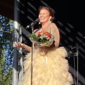 Arja Koriseva hymyilee palkinto ja kukkapuska kädessään