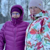 Kaksi naista seisoo sillalla talvisessa maisemassa.