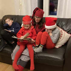 Äiti lukee lapsille jouluaiheista kirjaa.