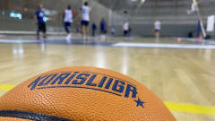 Korpiallo, jonka taustalla näkyy sumeana harjoittelevia Kataja Basketin pelaajia.