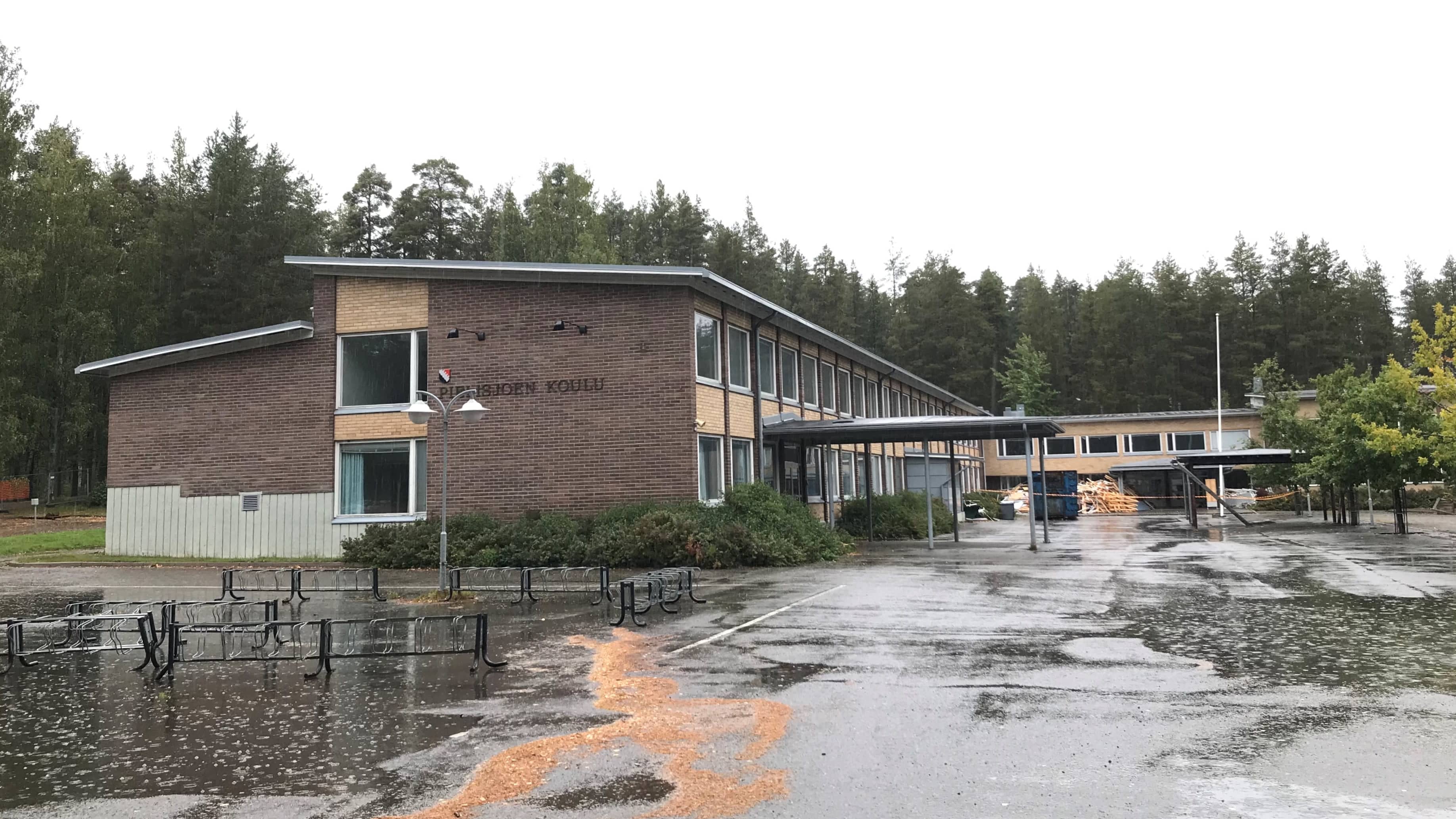Purettava koulurakennus näyttää hylätyltä vesisateessa.