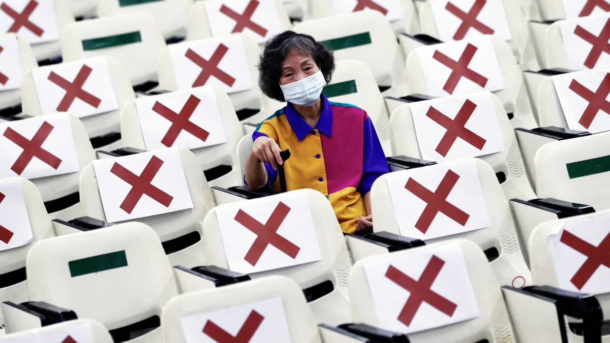 Juuri rokotuksen saanut kasvomaskiin pukeutunut henkilö istuu odottamassa mahdollisia sivuvaikutuksia rokotuskeskuksessa Taiwanissa.