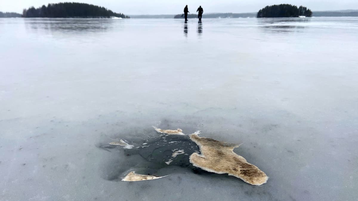Likaista vaahtoa avannon reunalla, taustalla kalastajia jäällä.