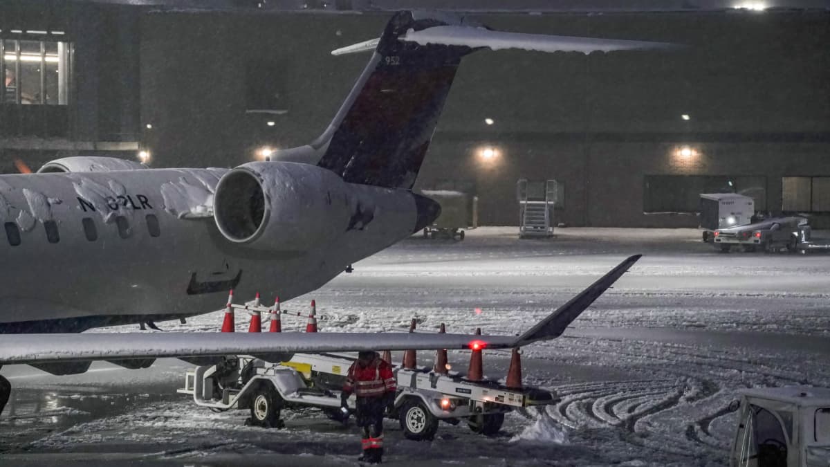 Lentokenttätyöntekijä kävelee kiitotien läpi lumimyrskyn aikana.
