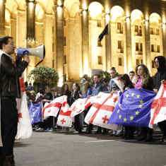 Mielenosoittajia Georgian parlamenttitalon edustalla. Monella on mukanaan joko Georgian tai EU:n lippu.