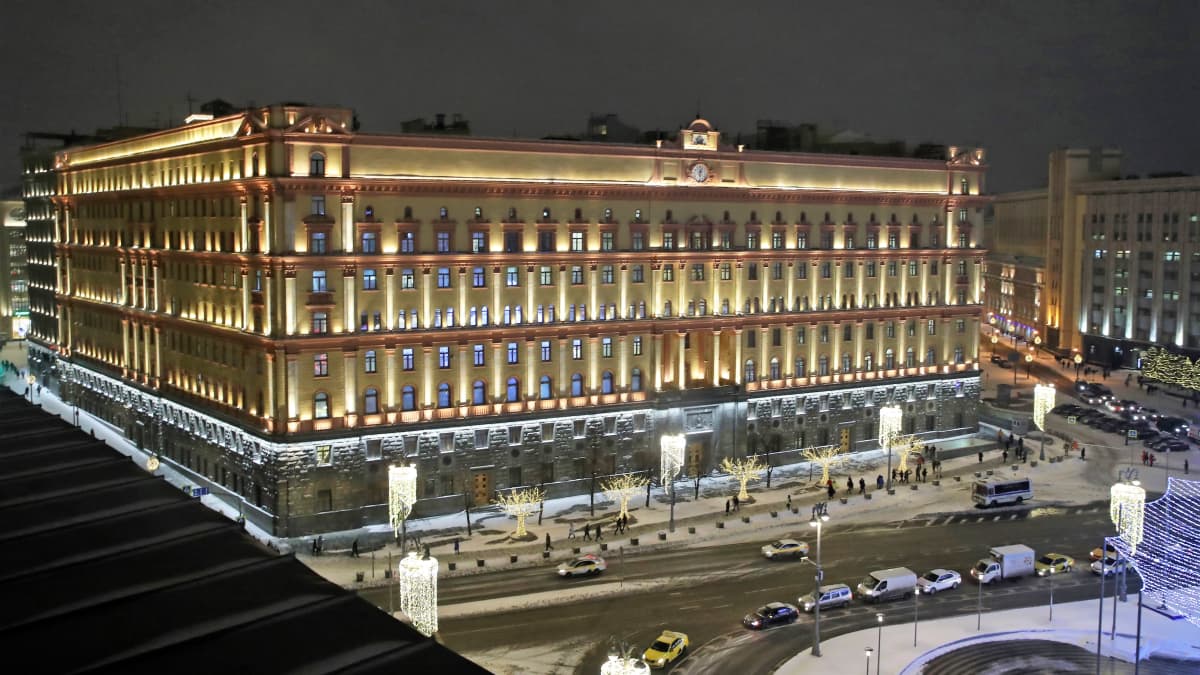 Venäjän turvallisuuspalvelun massiivisen uusbarokkisen päämajan julkisivut talvi-iltana. Rakennus on aukion laidalla. Kadulla sen edessä kulkee autoja. Maassa on lunta.