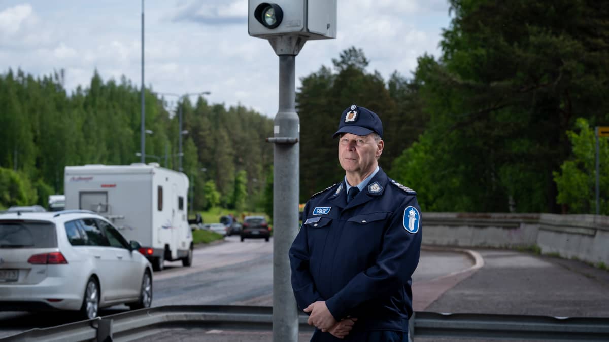 Poliisitarkastaja Heikki Ihalainen Poliisihallituksesta kuvattuna valtatie 12:n varrella Lahden Kärpäsenmäellä. Vieressä liikenteen nopeusvalvontakamera eli peltipoliisi eli kameratolppa. 