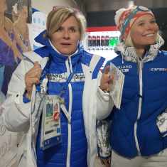 Kaksi naista Suomen olympiajoukkueen sinivalkoisissa vaatteissa näyttävät jännittävän urheilukilpailua.