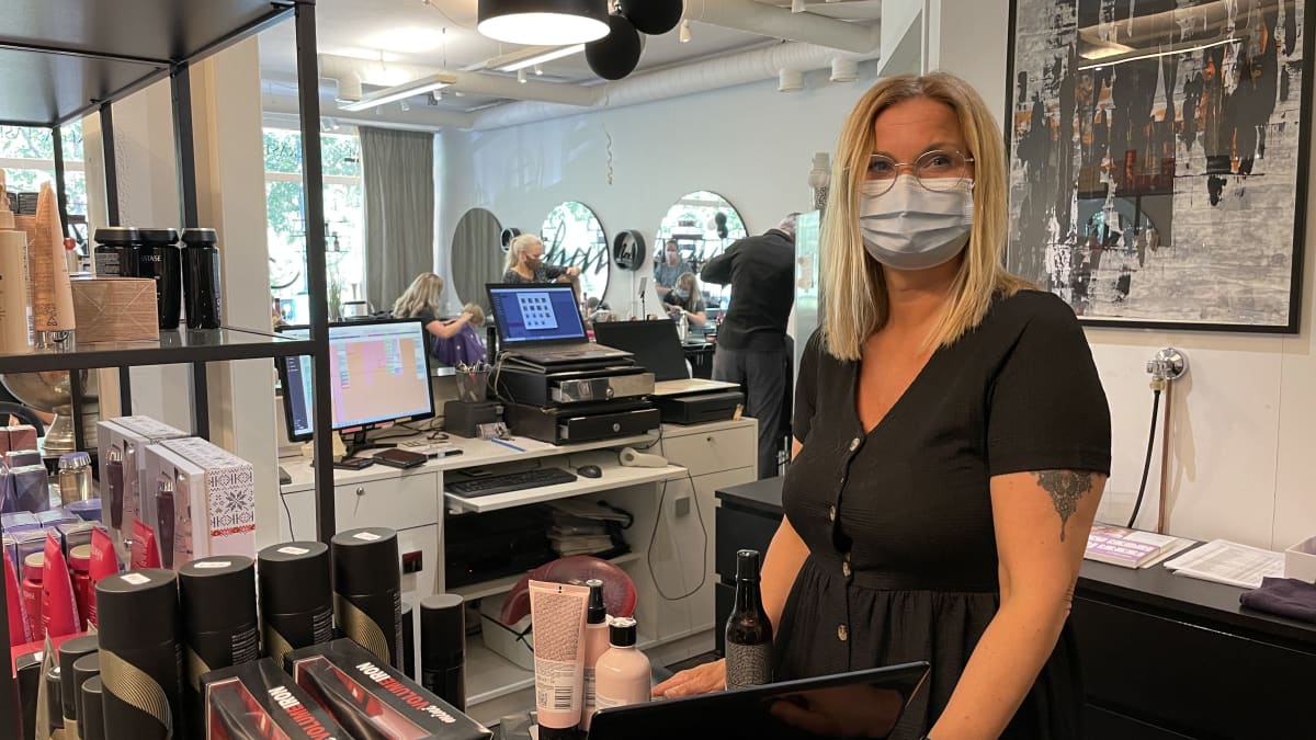 Kampaamoyrittäjä Maria Karp seisoo tiskin takana.